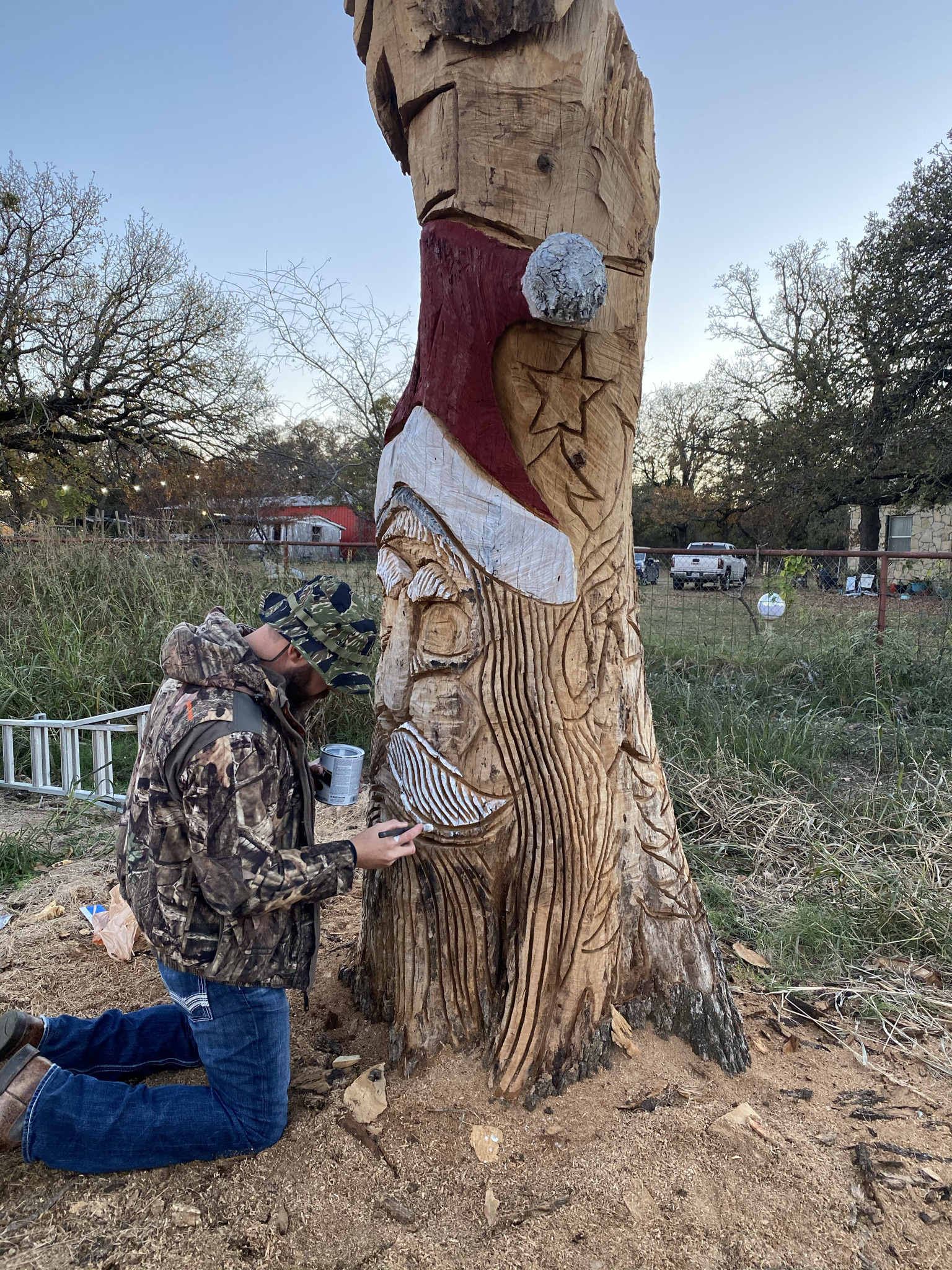 Carved Santa in a tree with a man painting the tree at Haynie's Gree Acres